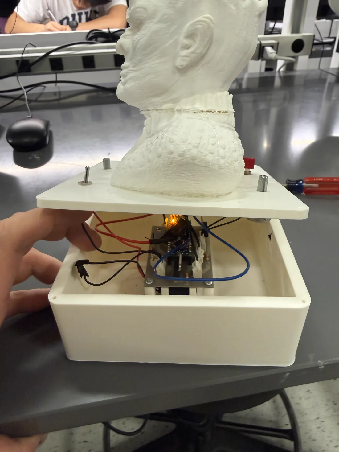 The printed enclosure with its lid lifted off, showing the assembled circuit board mounted on pillars inside and wiring running out to the LEDs and the 9 V cell.